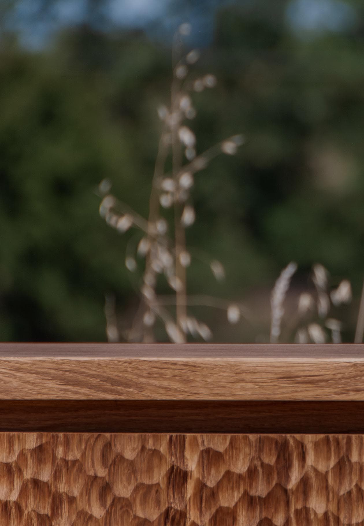 Gros plan sur la sculpture du bois de chêne du Buffet dessiné par Plié Architectes, mettant en avant le travail artisanal et la texture du matériau.